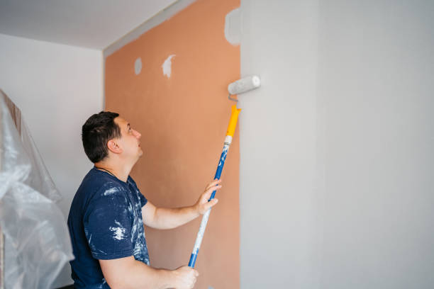 Mid-adult male painter painting the walls in a white color.